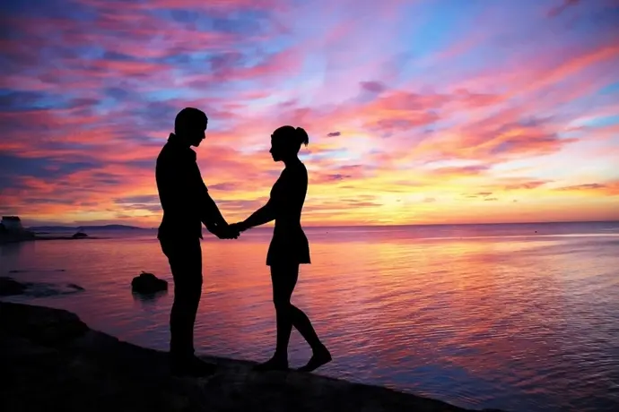 夕日をバックに手を繋ぐ男女のシルエット