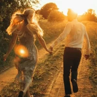 夕日をバックに手を繋いで走る男女