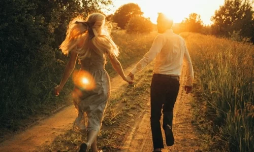 夕日をバックに手を繋いで走る男女